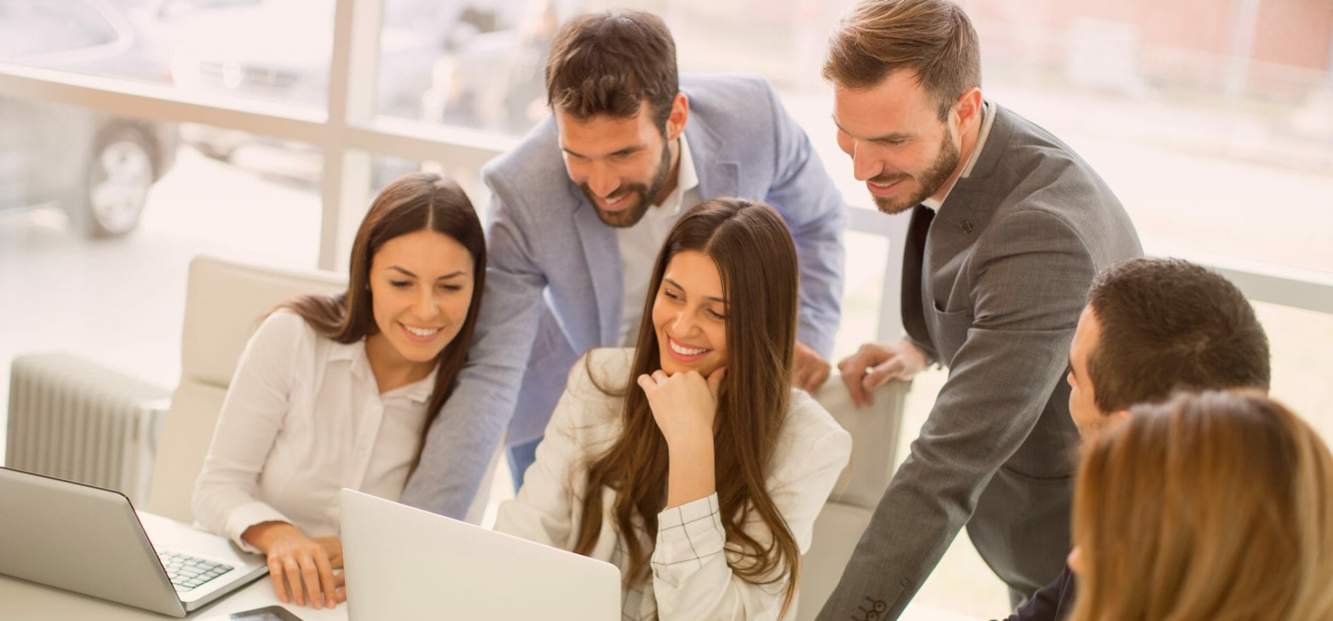 Groupe de 6 collègues partageant des connaissances tout en regardant un ordinateur portable.