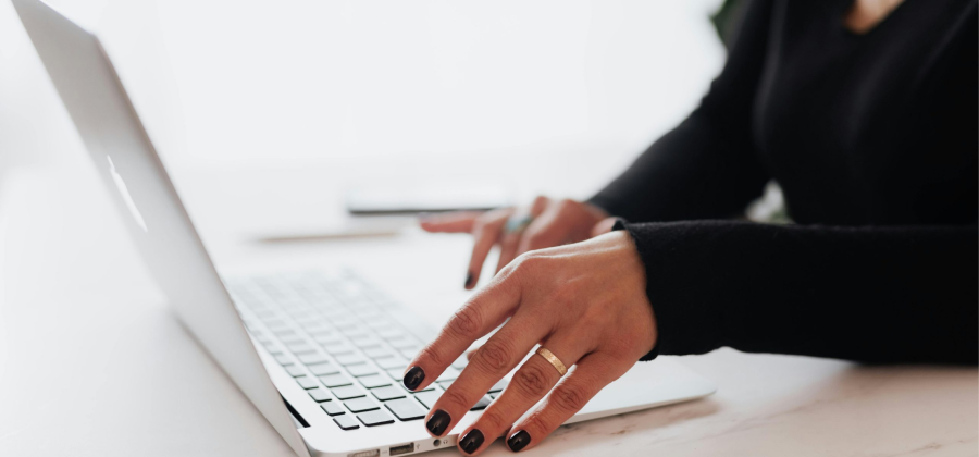 A person with black nail polish types on a laptop, crafting strategies on how to make online courses more interactive.